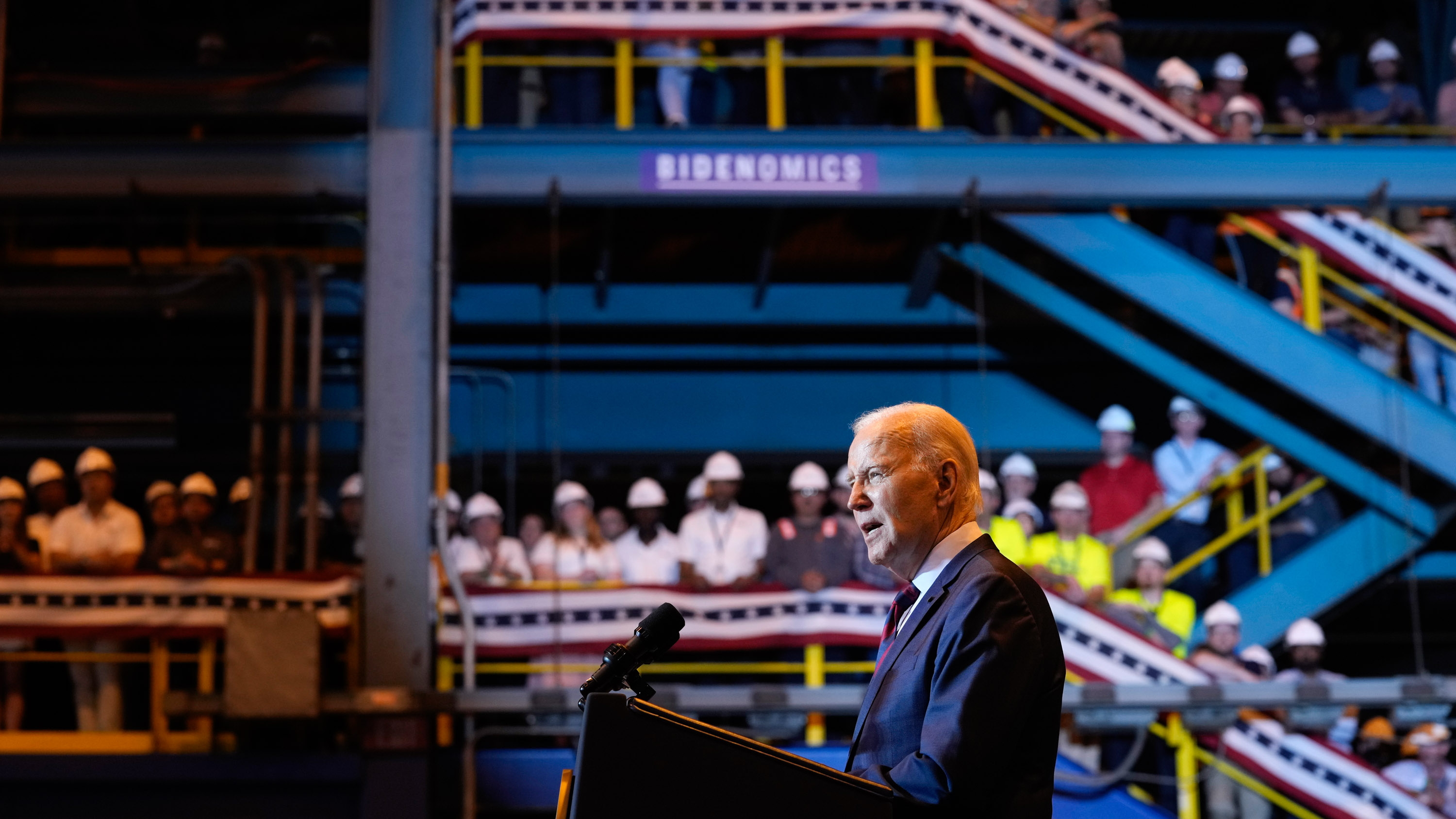 President Joe Biden speaks at a shipyard in Philadelphia with workers in hardhats in the audience