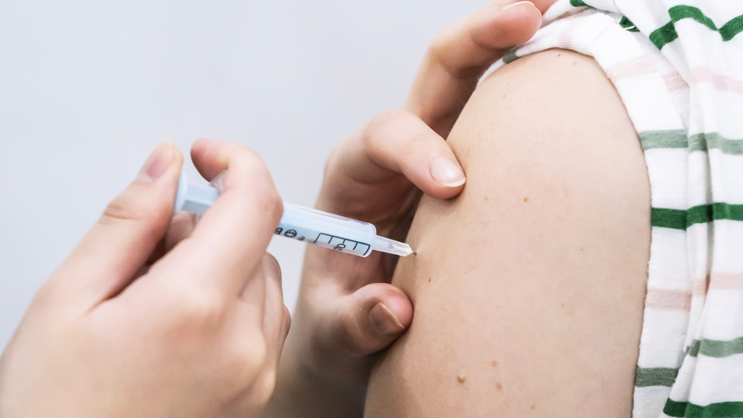 closeup on a shoulder where a booster coronavirus vaccine is being administered
