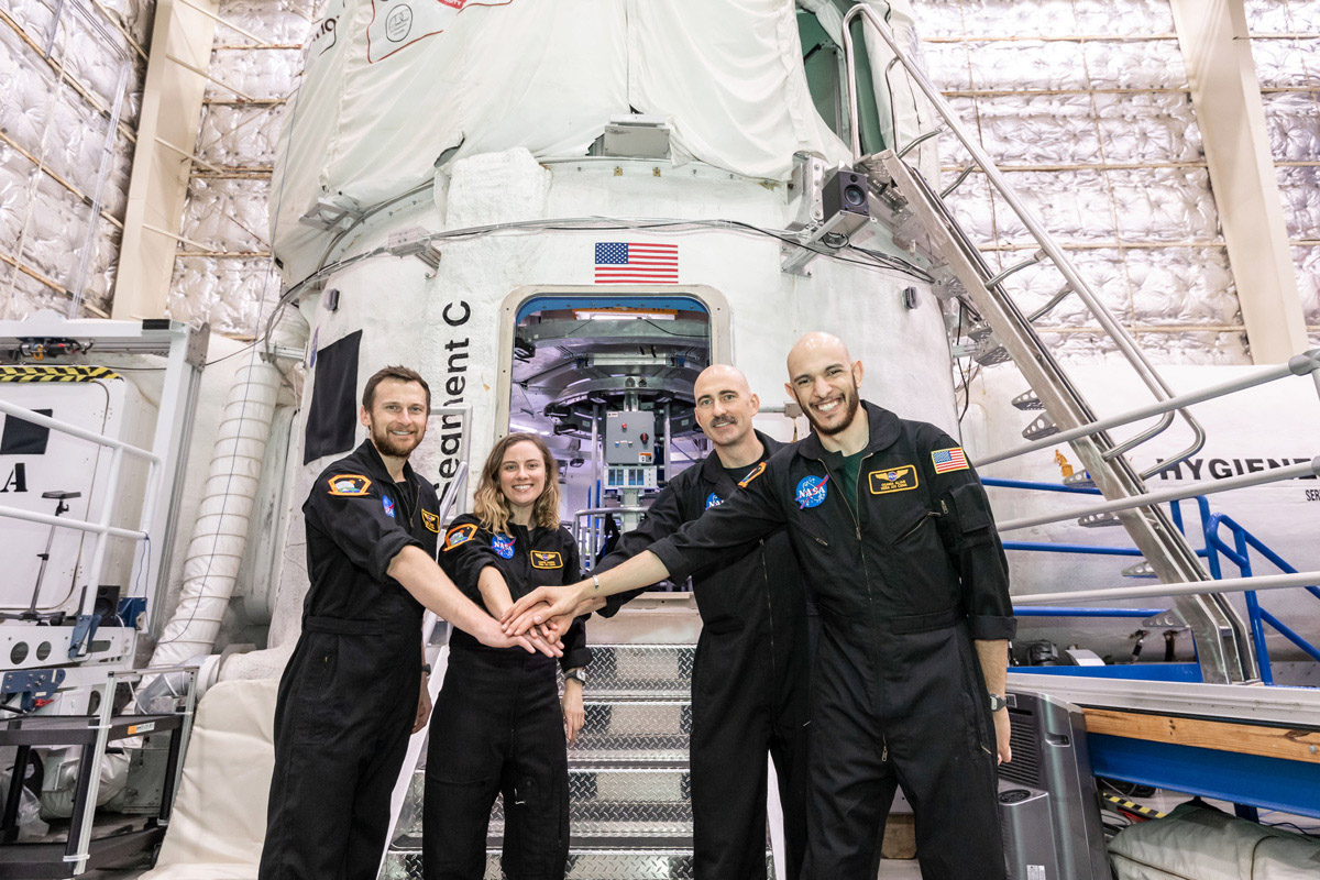 Analog astronauts stand with their hand together