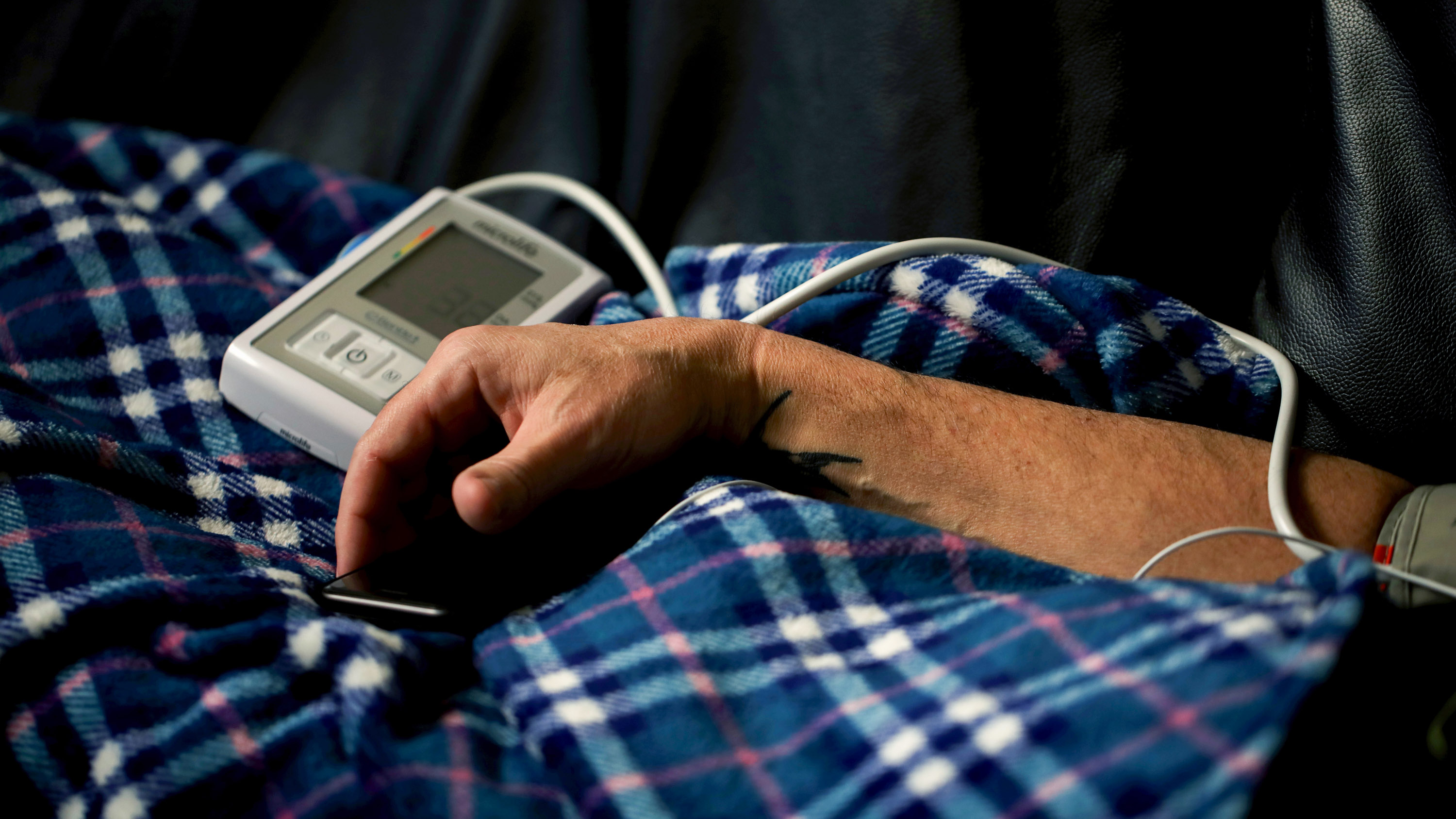 the arm of a patient resting on a plaid blanket while connected to a monitor at a ketamine clinic
