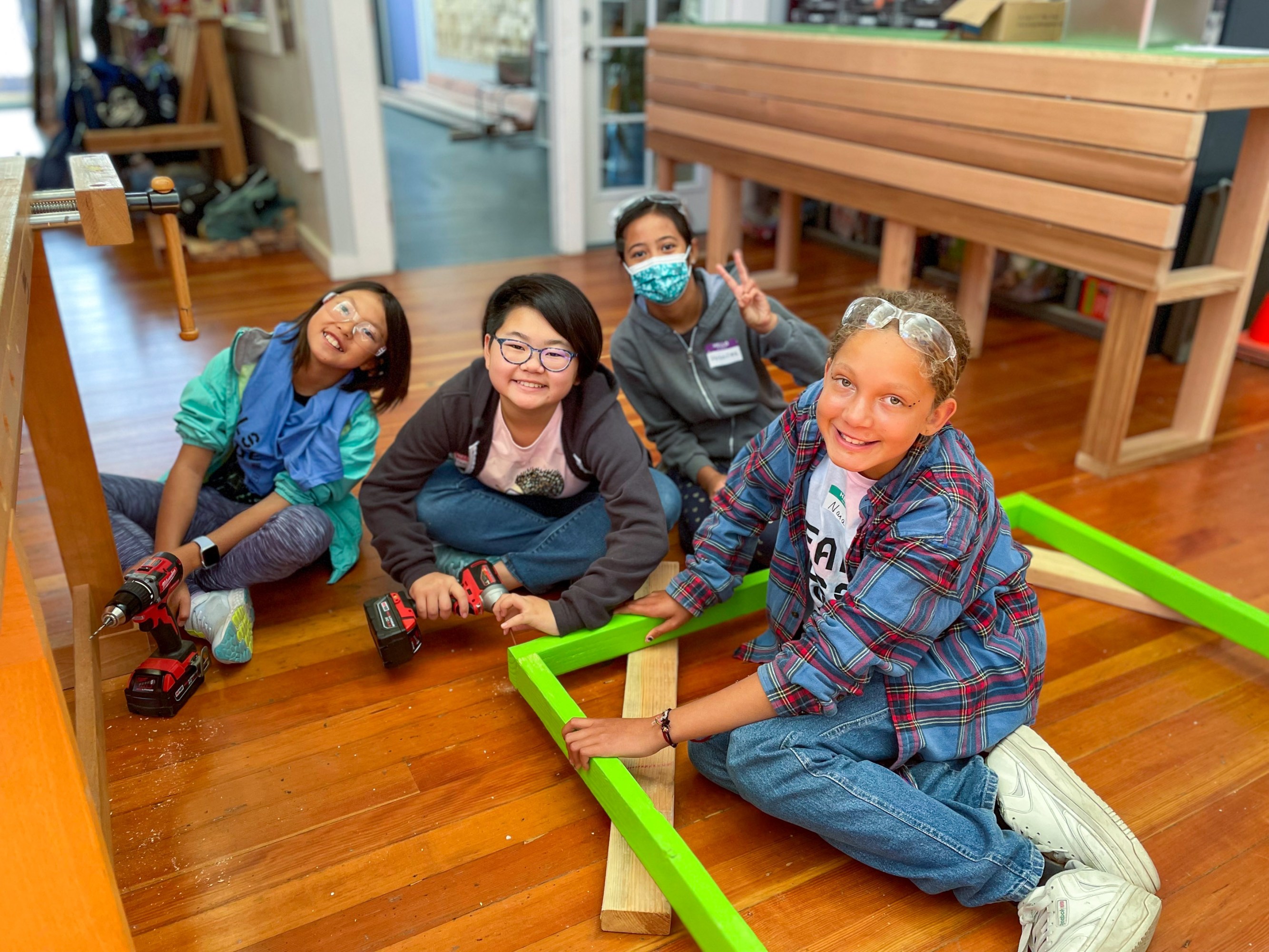 four middle-school age girls sitting on the floor to pose for photo