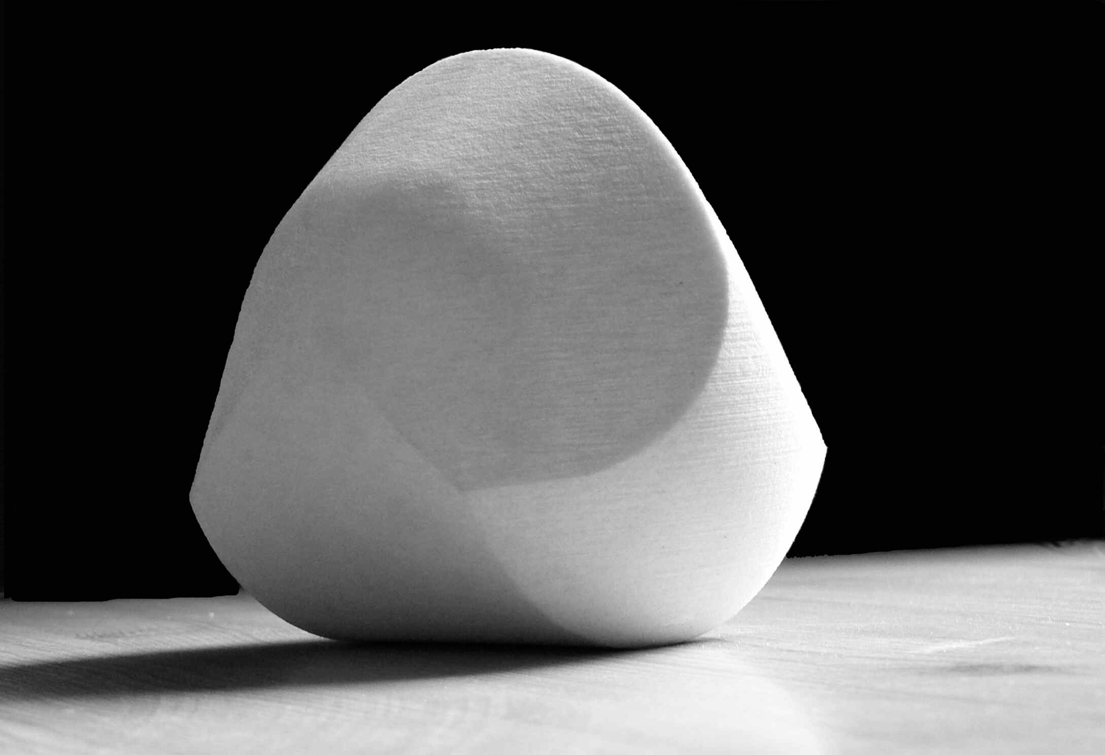 a white gömböc-shaped object starkly lit