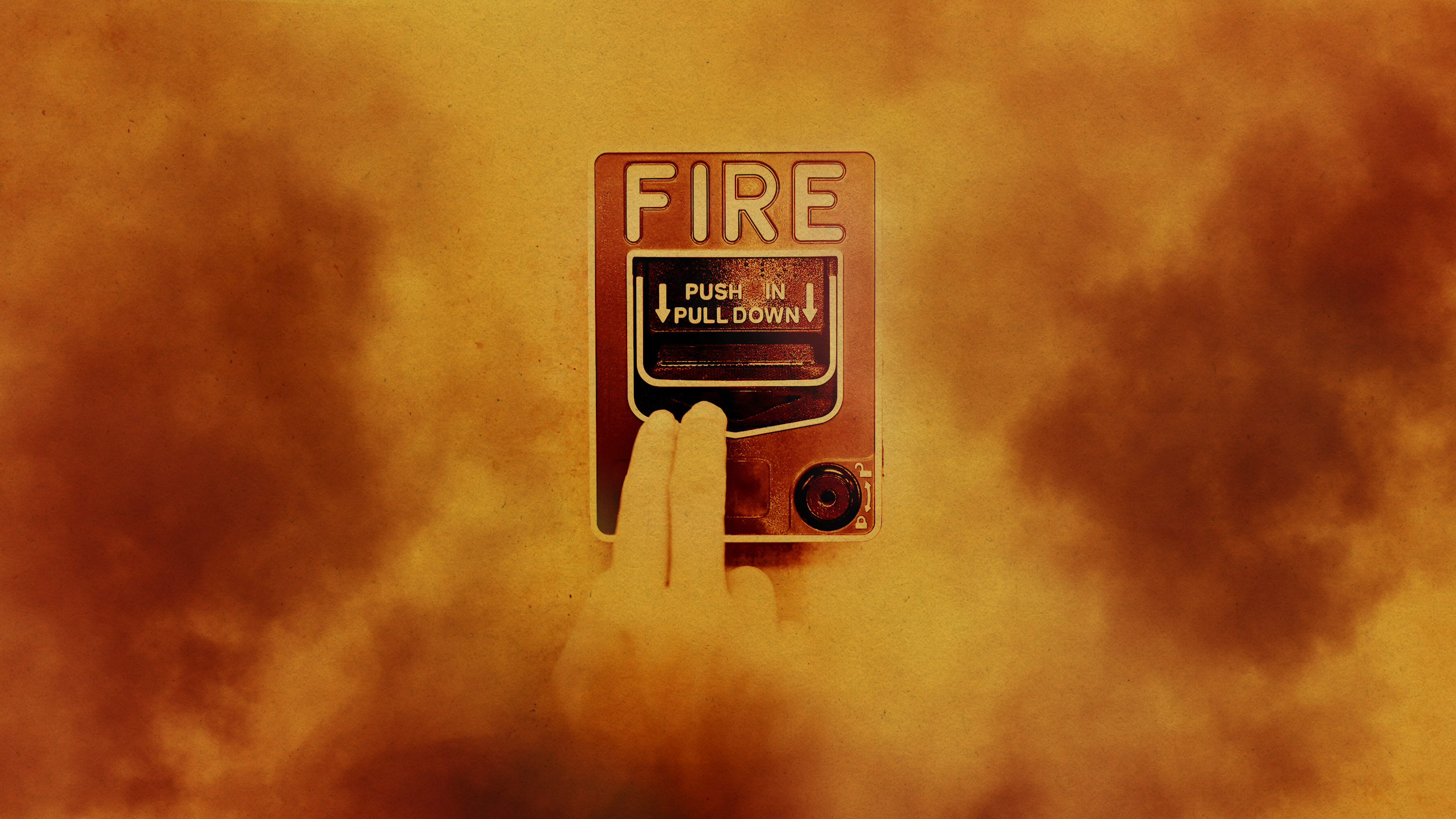 hand on a fire alarm seen through a thick haze of smoke