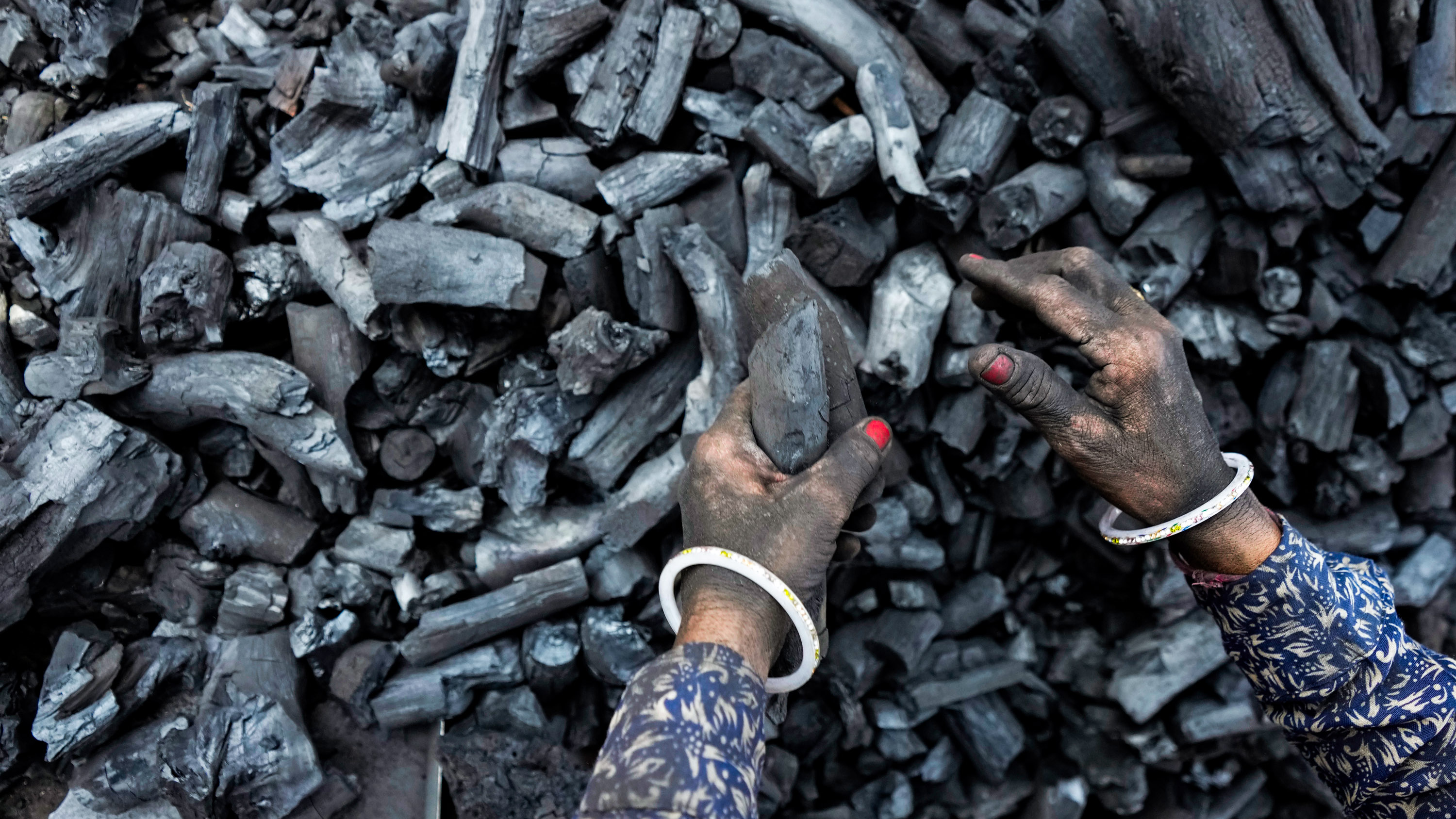 Hands of a woman sifting through pieces at a coal depot
