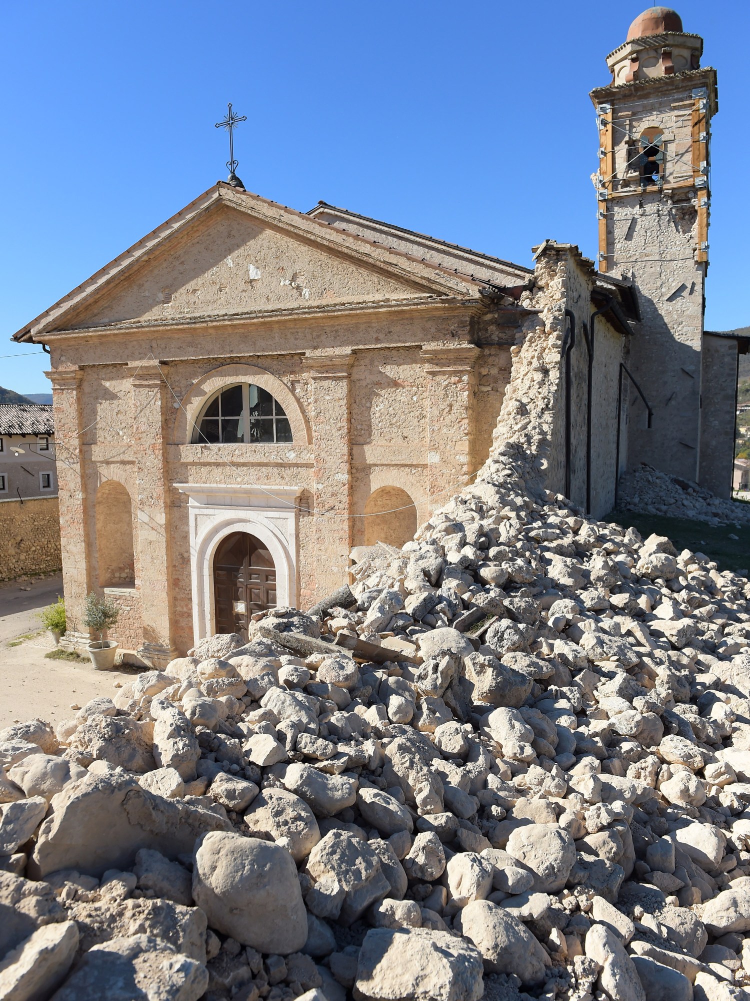 an old church seen standing past a massive pile of rubble in the foreground