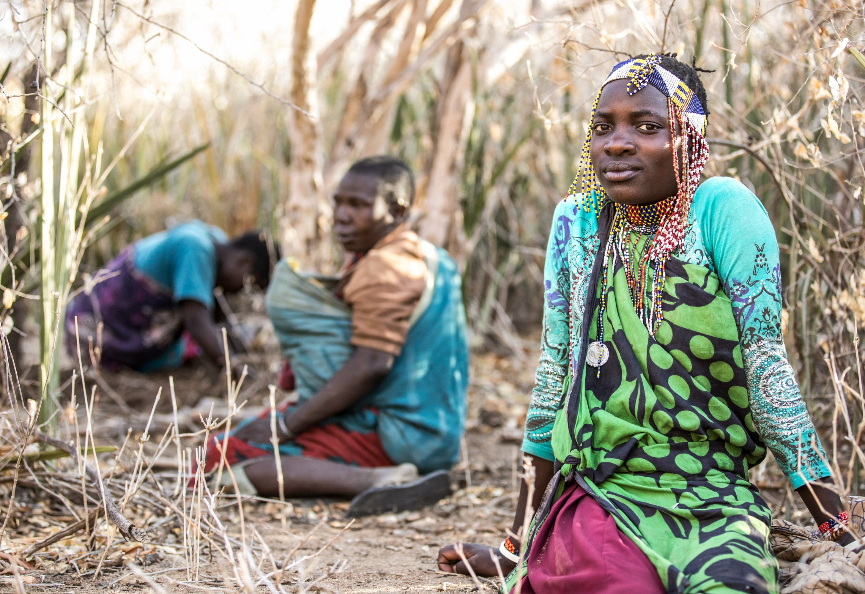 Hadza women sitting on the ground in the tall grass