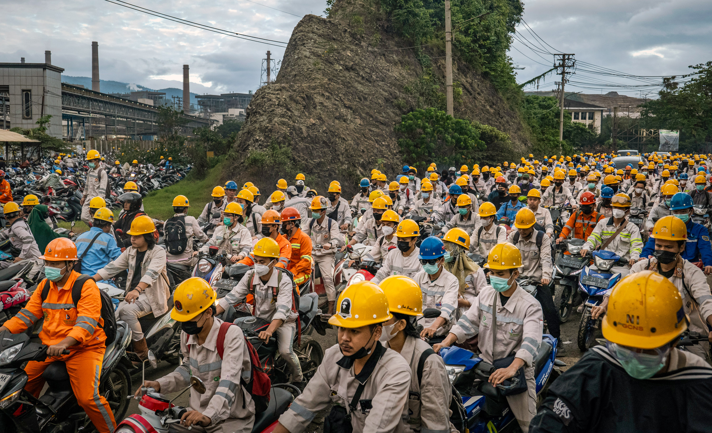 workers on motorbikes with mining helmets in a large traffic jam