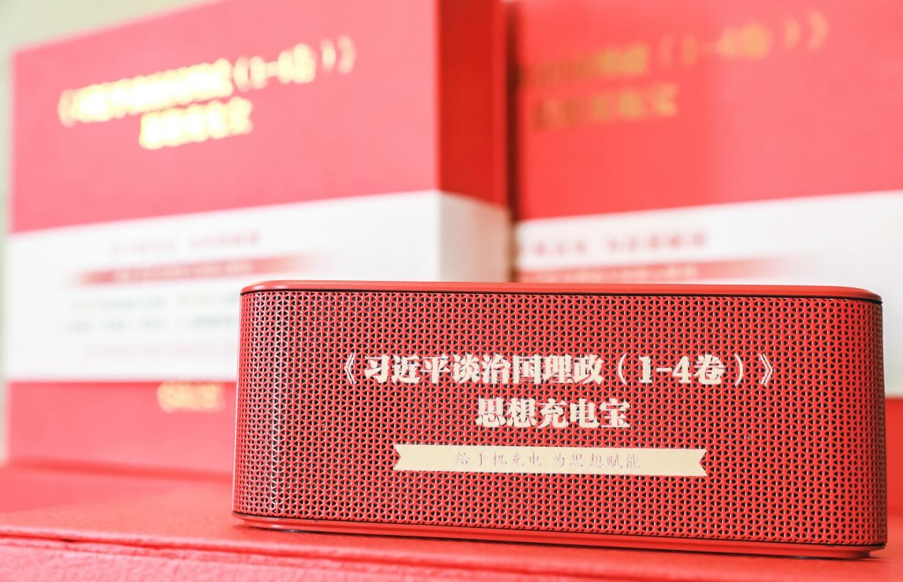 A red power bank and speaker with the Chinese characters "‘Xi Jinping’s “The Governance of China” Volumes 1-4’ Ideology Power Bank" printed on it.