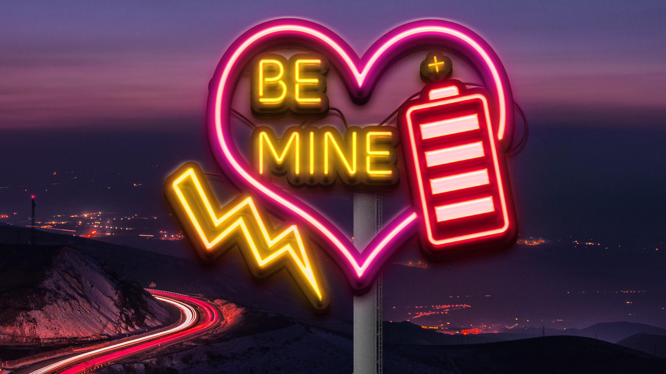 Large neon sign of a heart with a lightning bolt and battery with the words &quot;Be Mine&quot; overlooking a mountain pass road at night