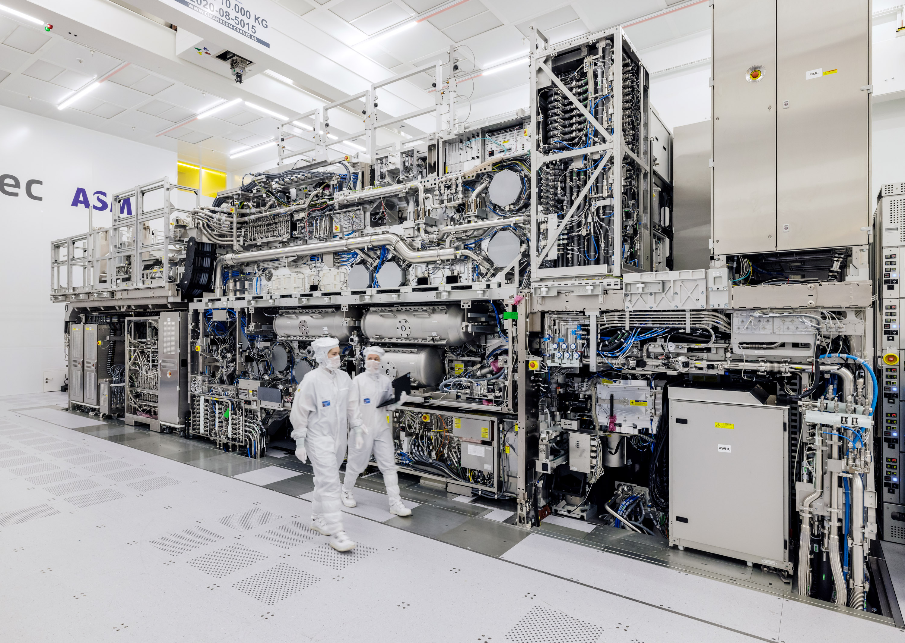 Two ASML workers walk past the High NA EUV machine in Veldhoven