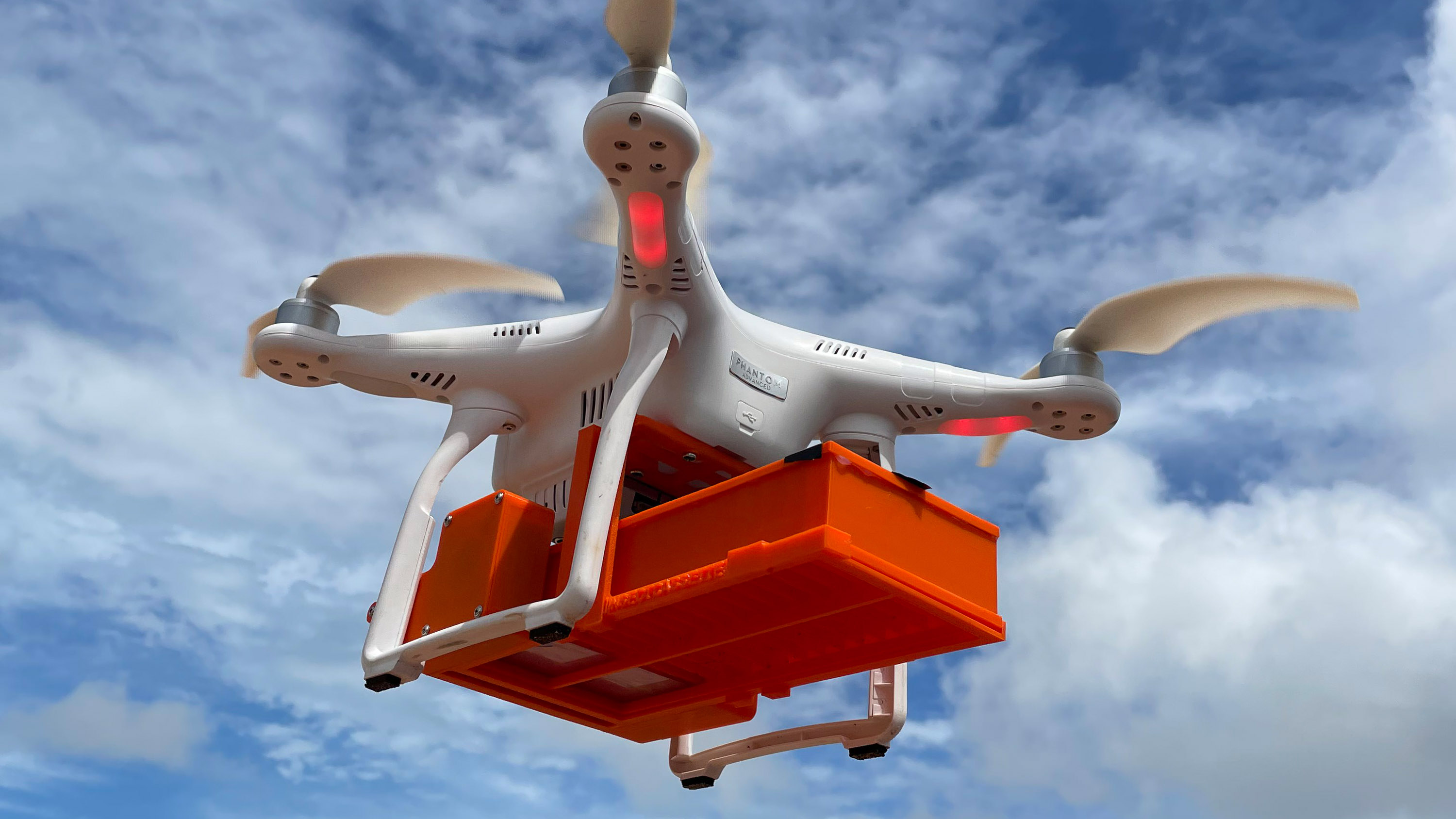 a birdview quadcopter drone carrying a bright orange cassette of insects