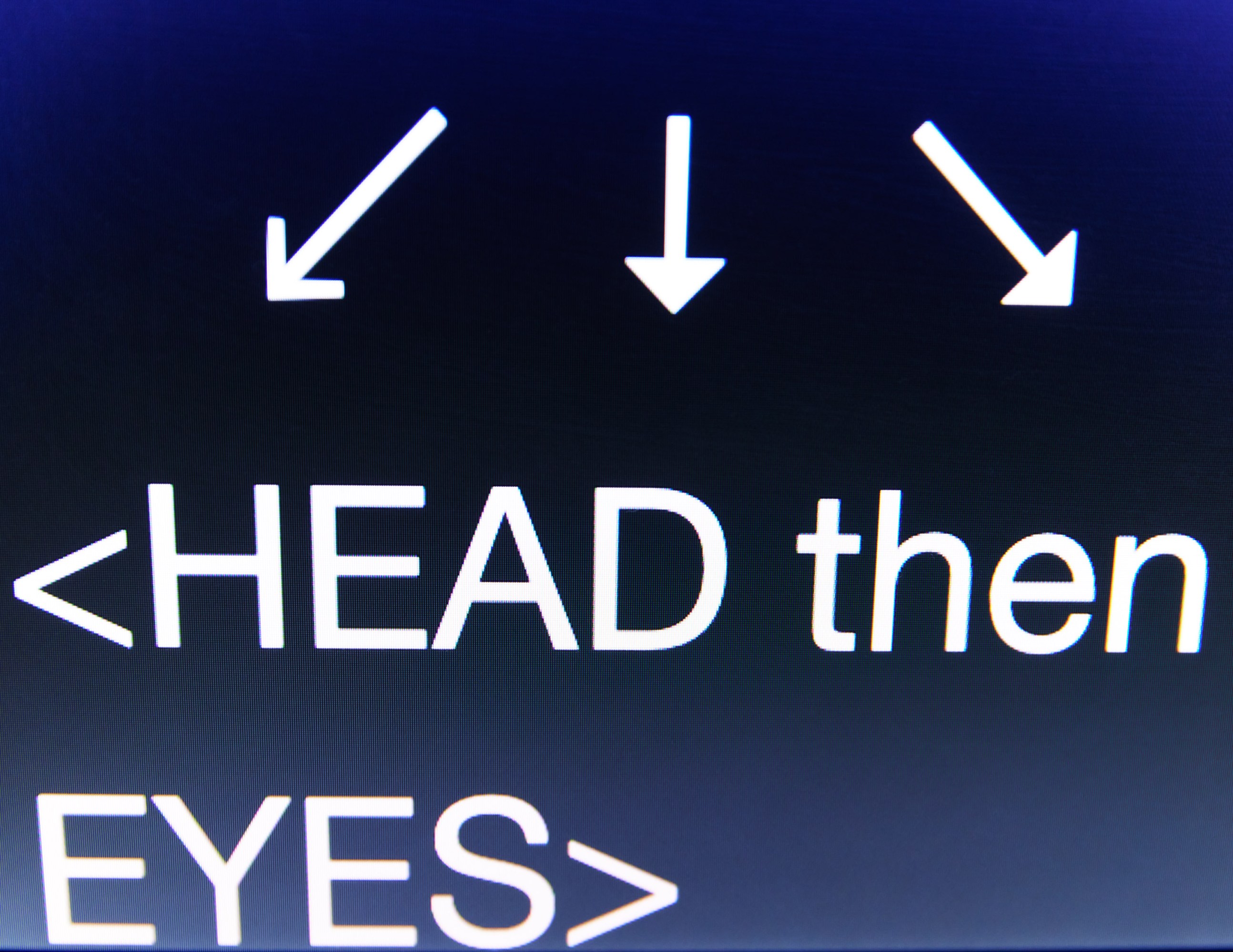 photograph of a teleprompter screen with three arrows pointing down to "HEAD then EYES>"