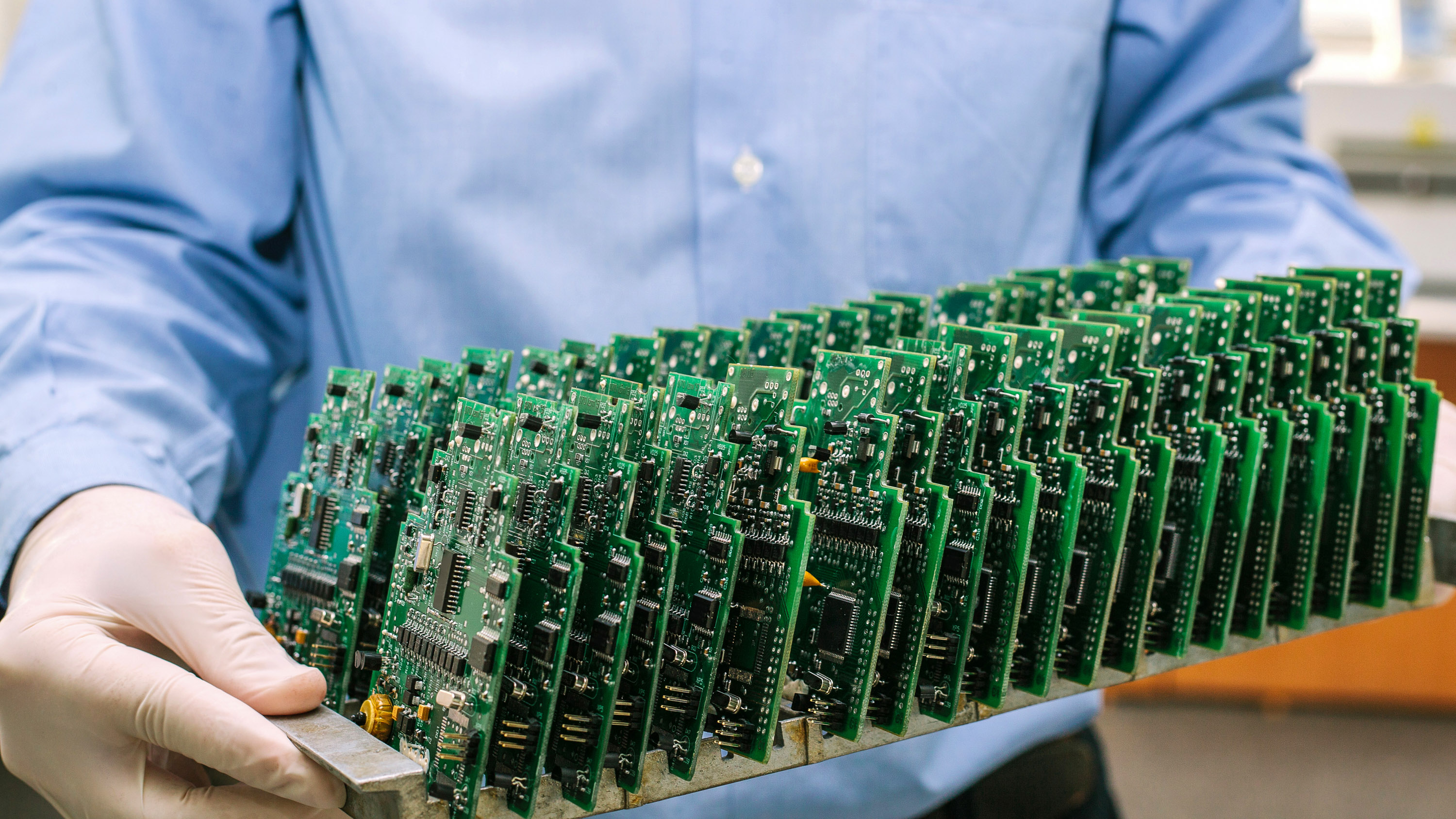 person in gloves holding a tray of pcb boards