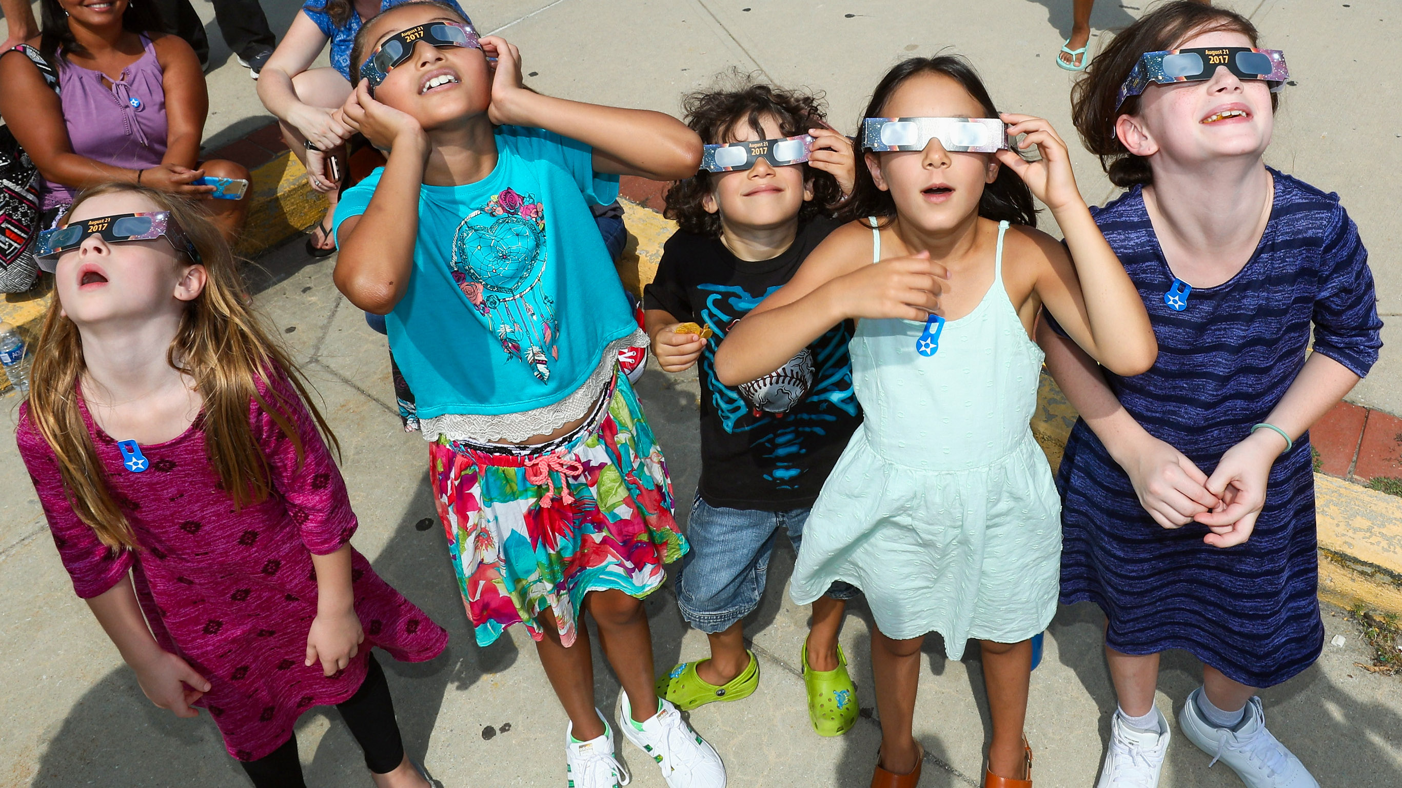 children looking up in wonder while wearing solar eclipse glasses