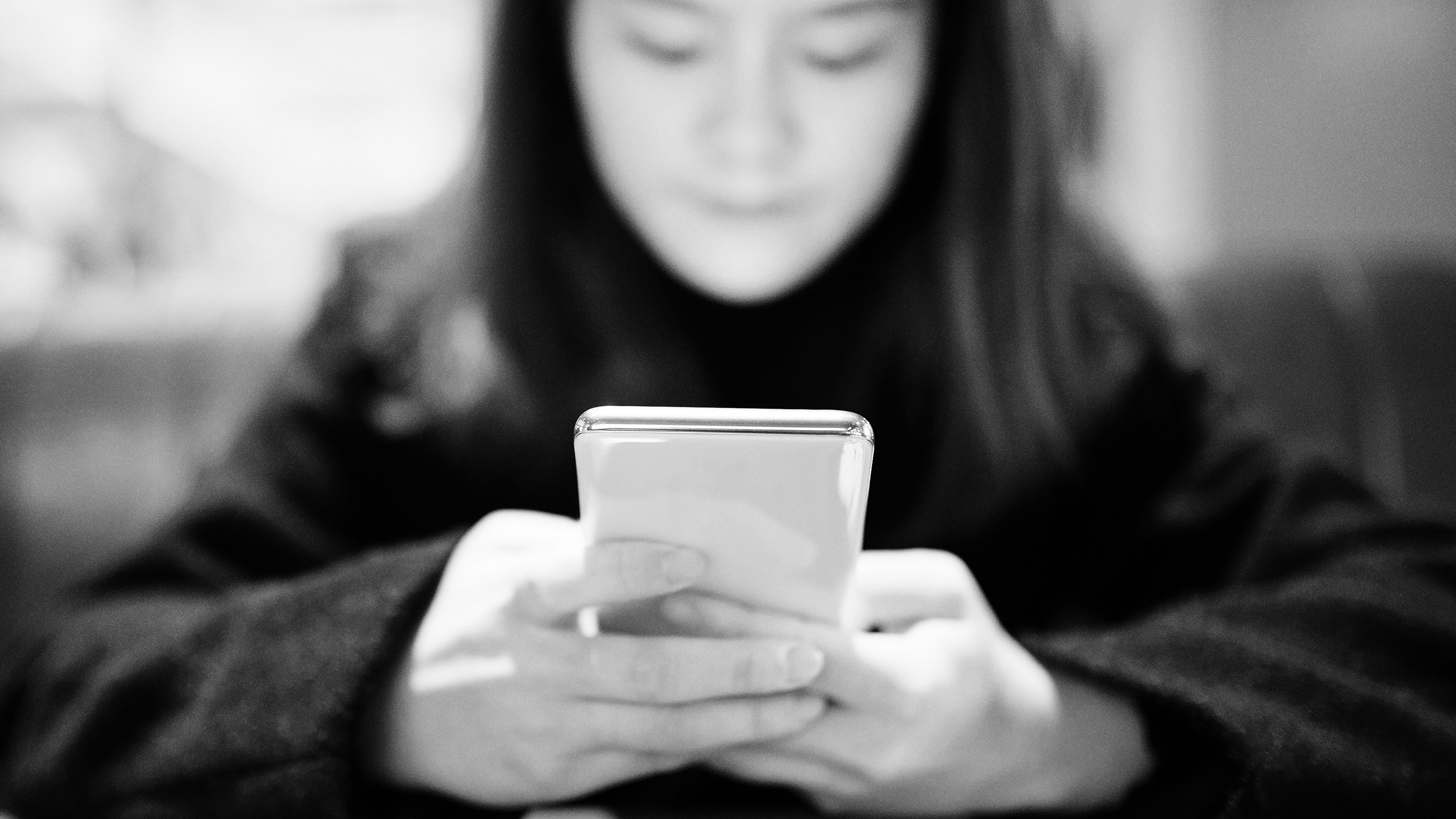 Young Chinese woman using smart phone in a restaurant.