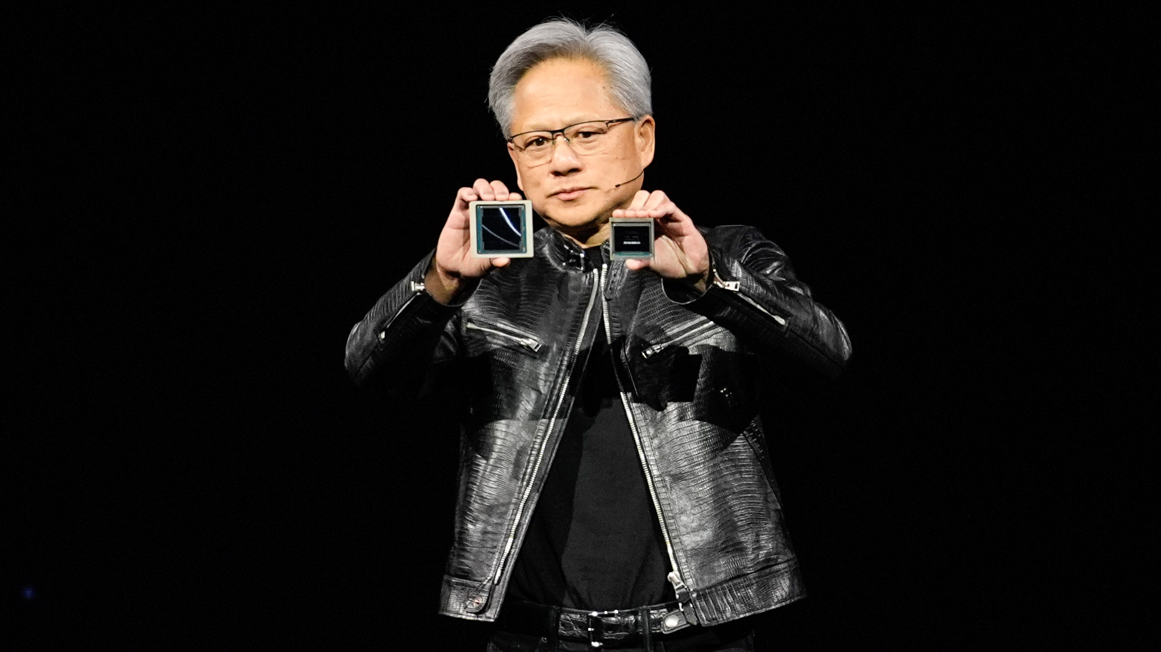 CEO Jensen Huang holds up chips on stage during a keynote address