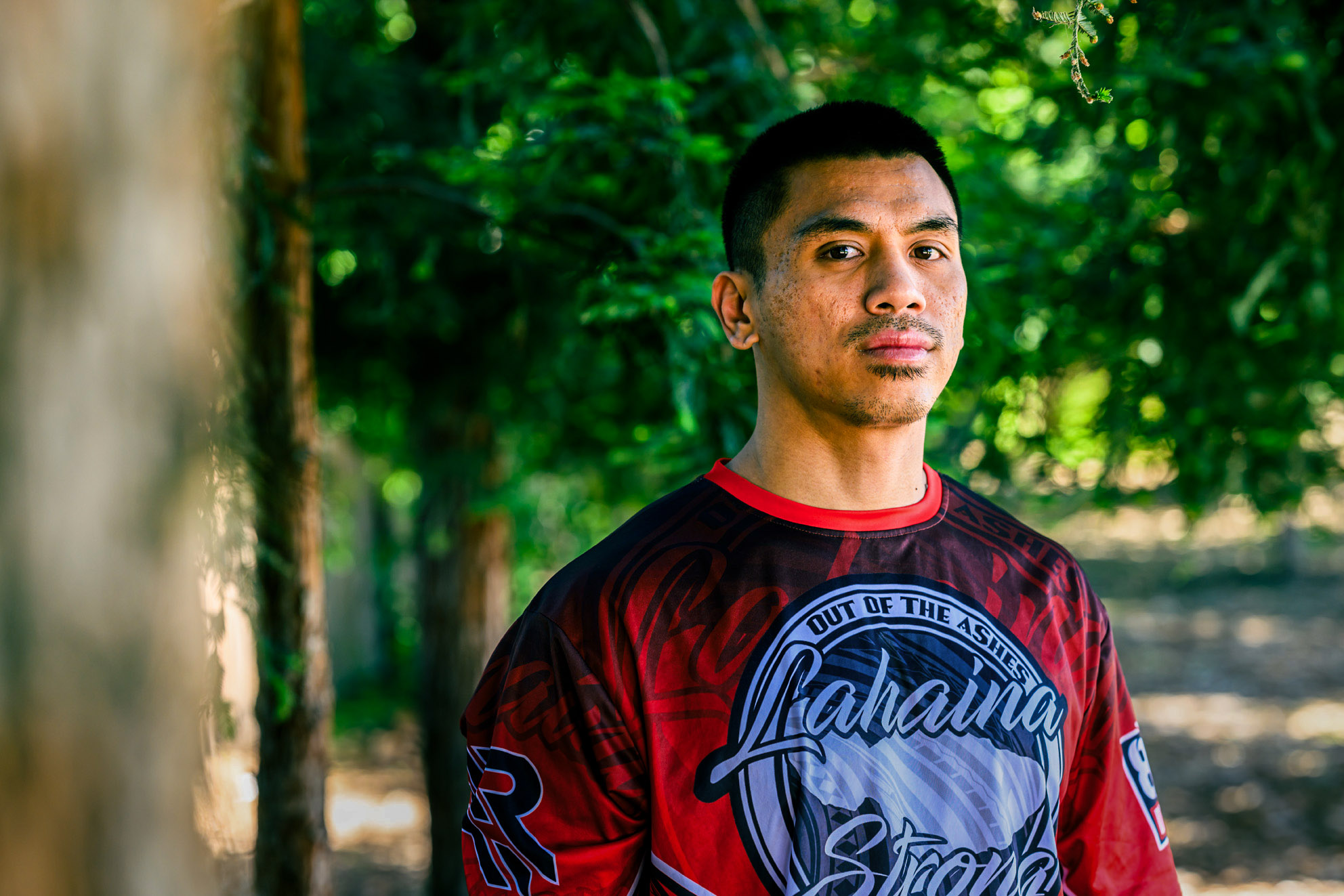 Raven Imperial standing in the shade of trees wearing a "Lahaina Strong; Out of the ashes" shirt