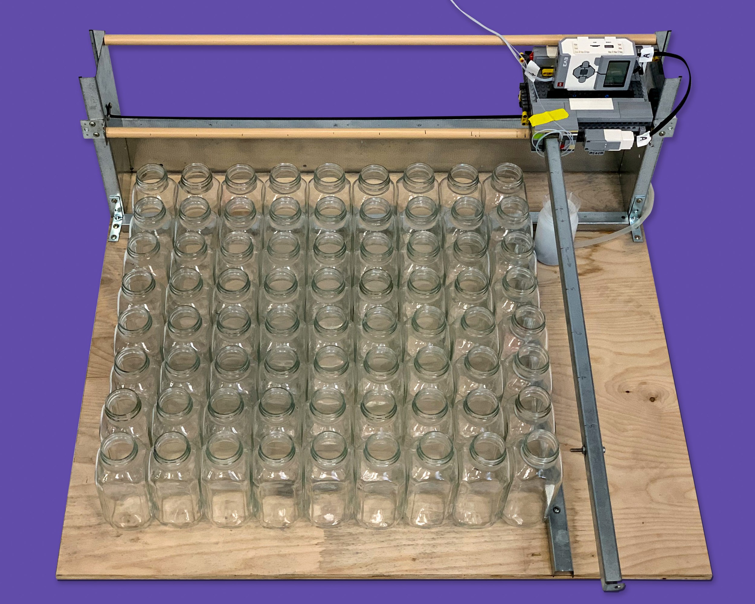 Board with a grid of glass bottles with a LEGO chromatographer  attached on a rail at rear